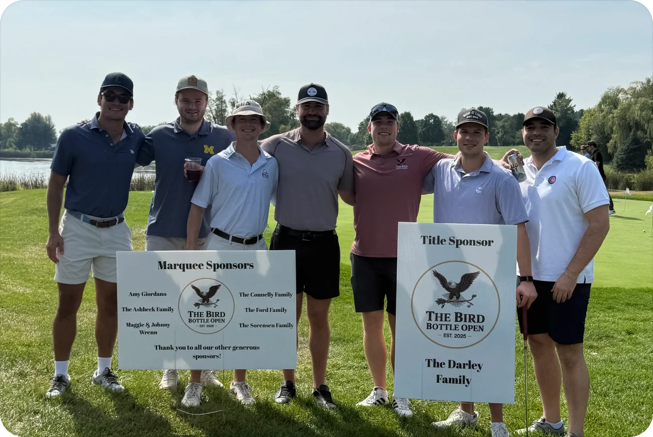 Seven men posing together next to Bird Bottle Open sponsor signs