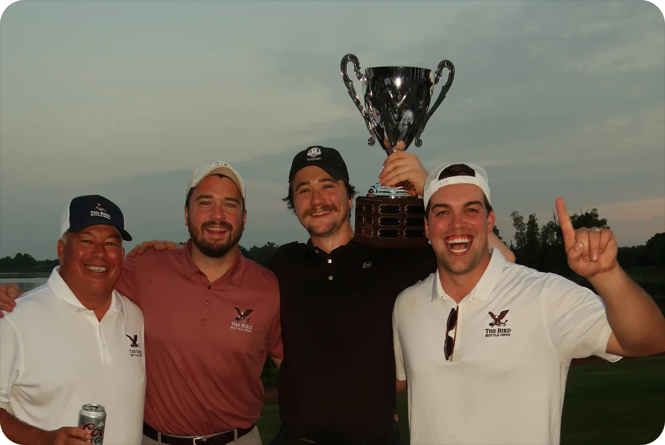 Four men celebrating and holding the Bird Bottle Open championship trophy aloft