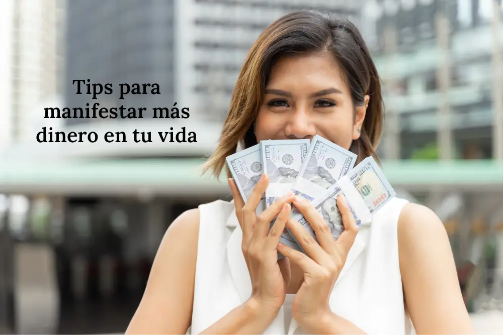 Mujer sonriendo sosteniendo fajos de billetes, ilustrando consejos para manifestar abundancia y atraer más dinero a la vida