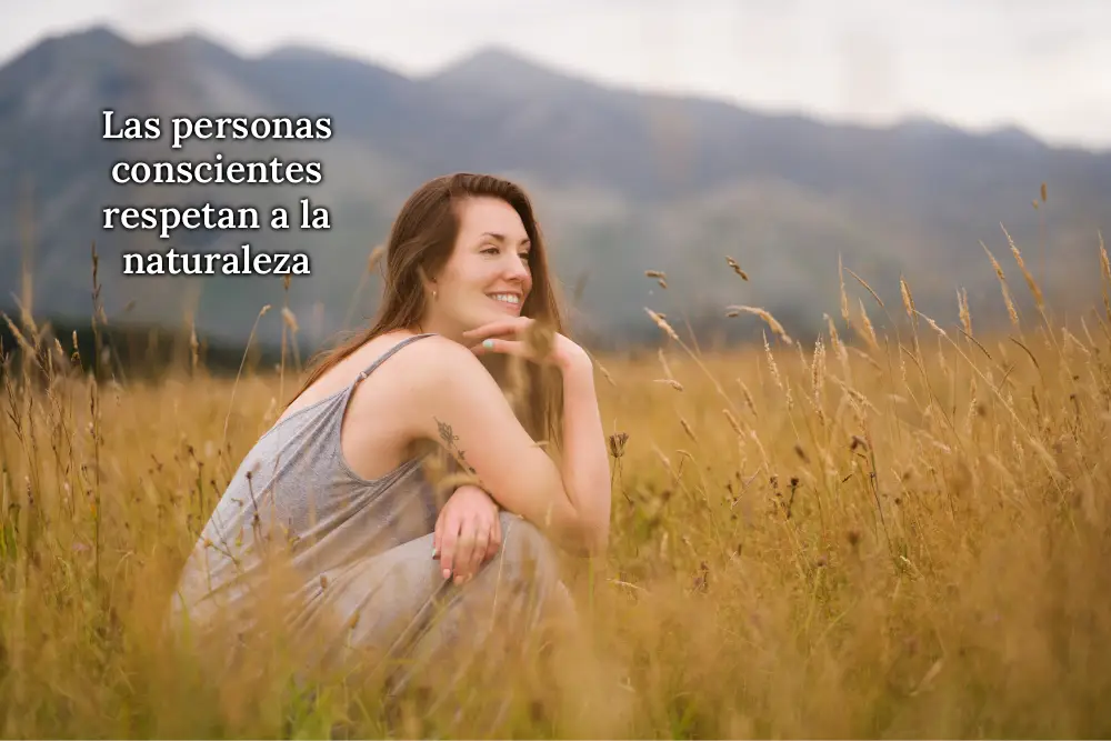 Mujer sonriente sentada en medio de la naturaleza en posición relajada, simbolizando conexión, respeto y armonía con el entorno natural, reflejando la conciencia ecológica