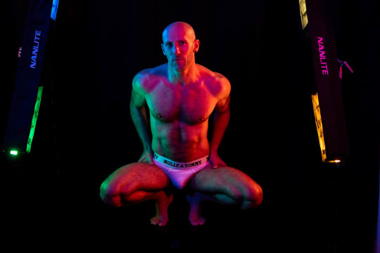 A man squatting in multicoloured lights