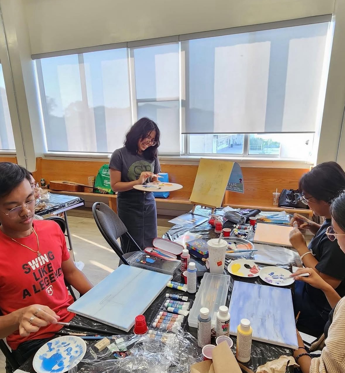 Art teacher and students mixing paint in their workspaces.