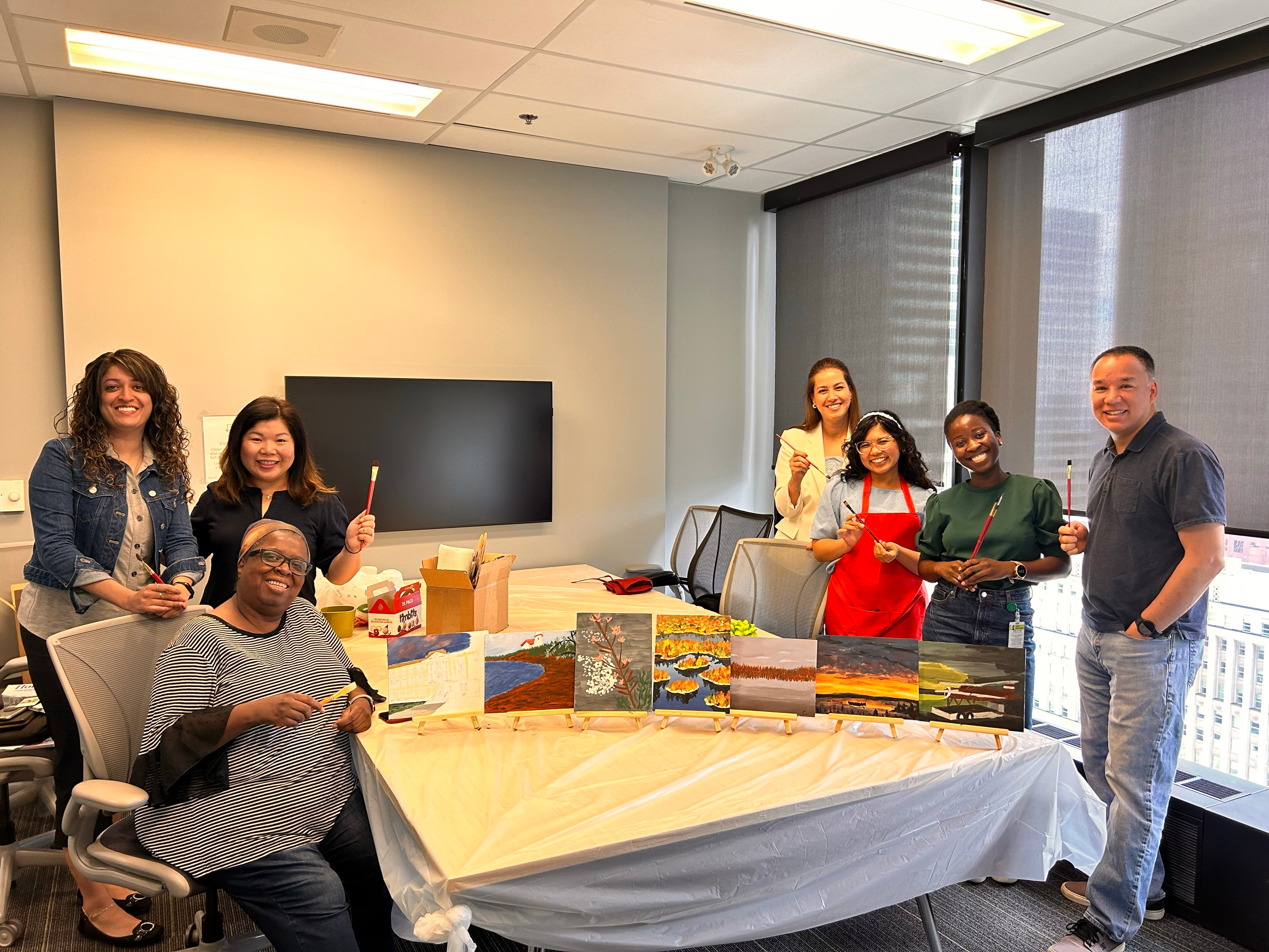 Group photo of employees on either side of a table showing painted pieces.