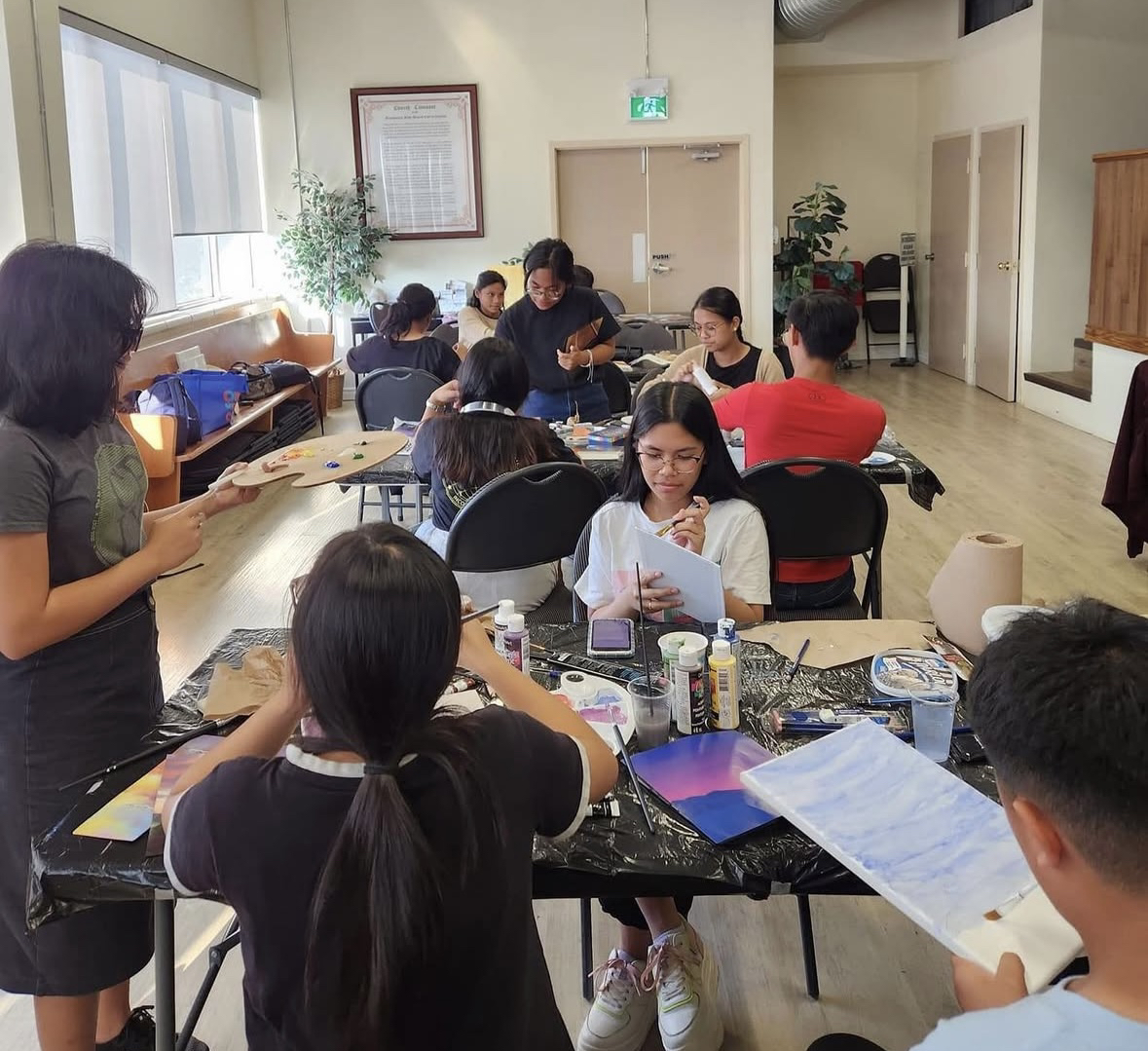 A view of a classroom featuring up to 10 students working on paintings.