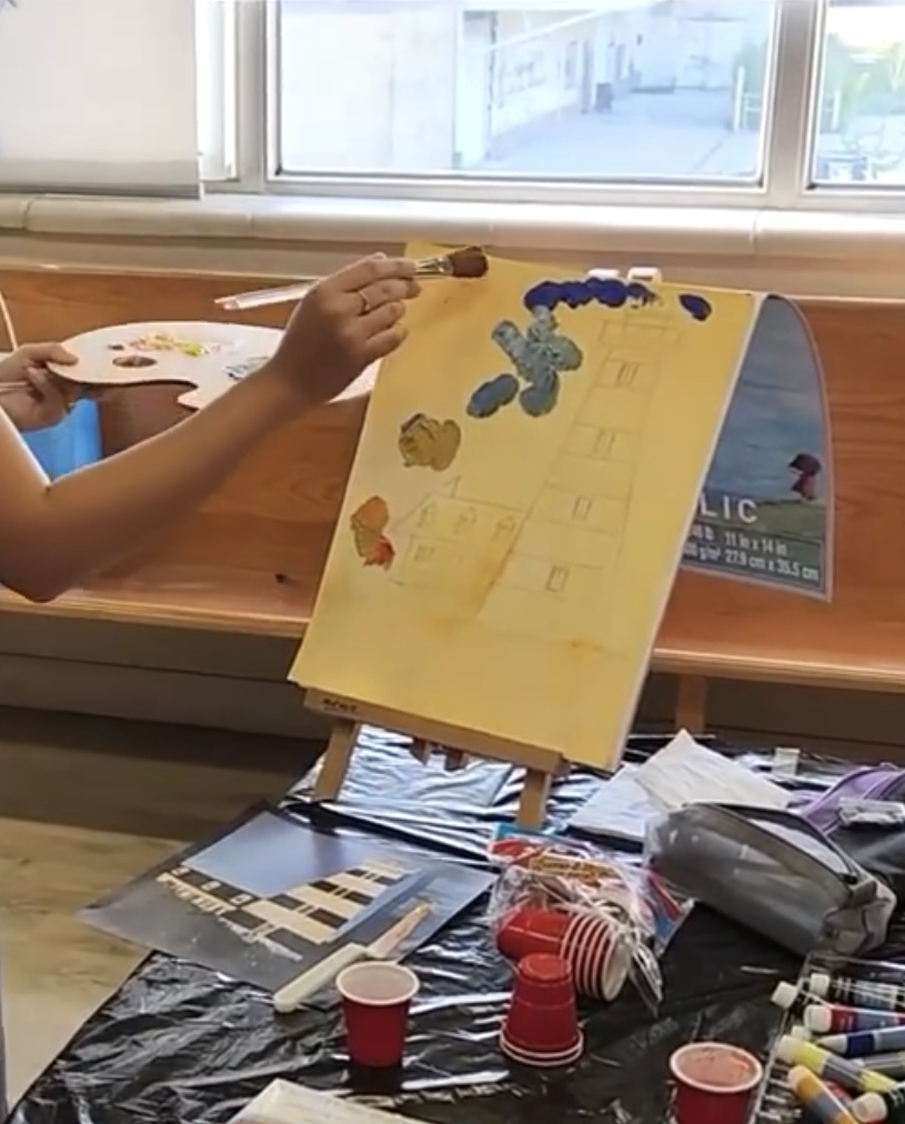 Art teacher holding a palette and brush, doing a demonstration on sky gradient blending.