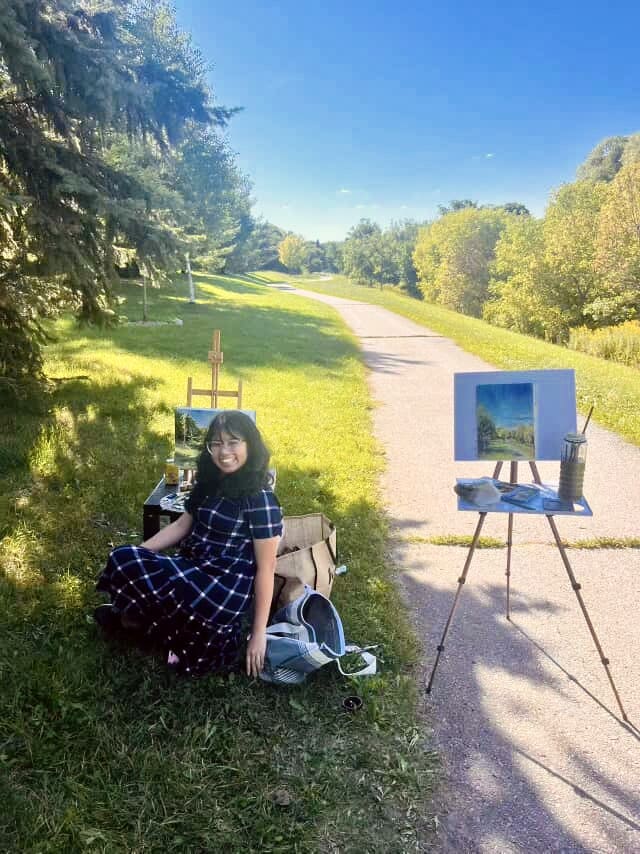 Andrea's artist portrait features a black haired woman with tan skin and burgundy sweater