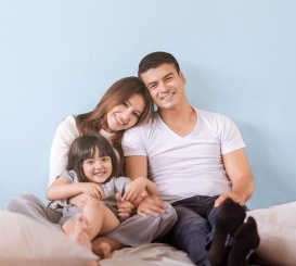 Happy asian family sitting on a bed