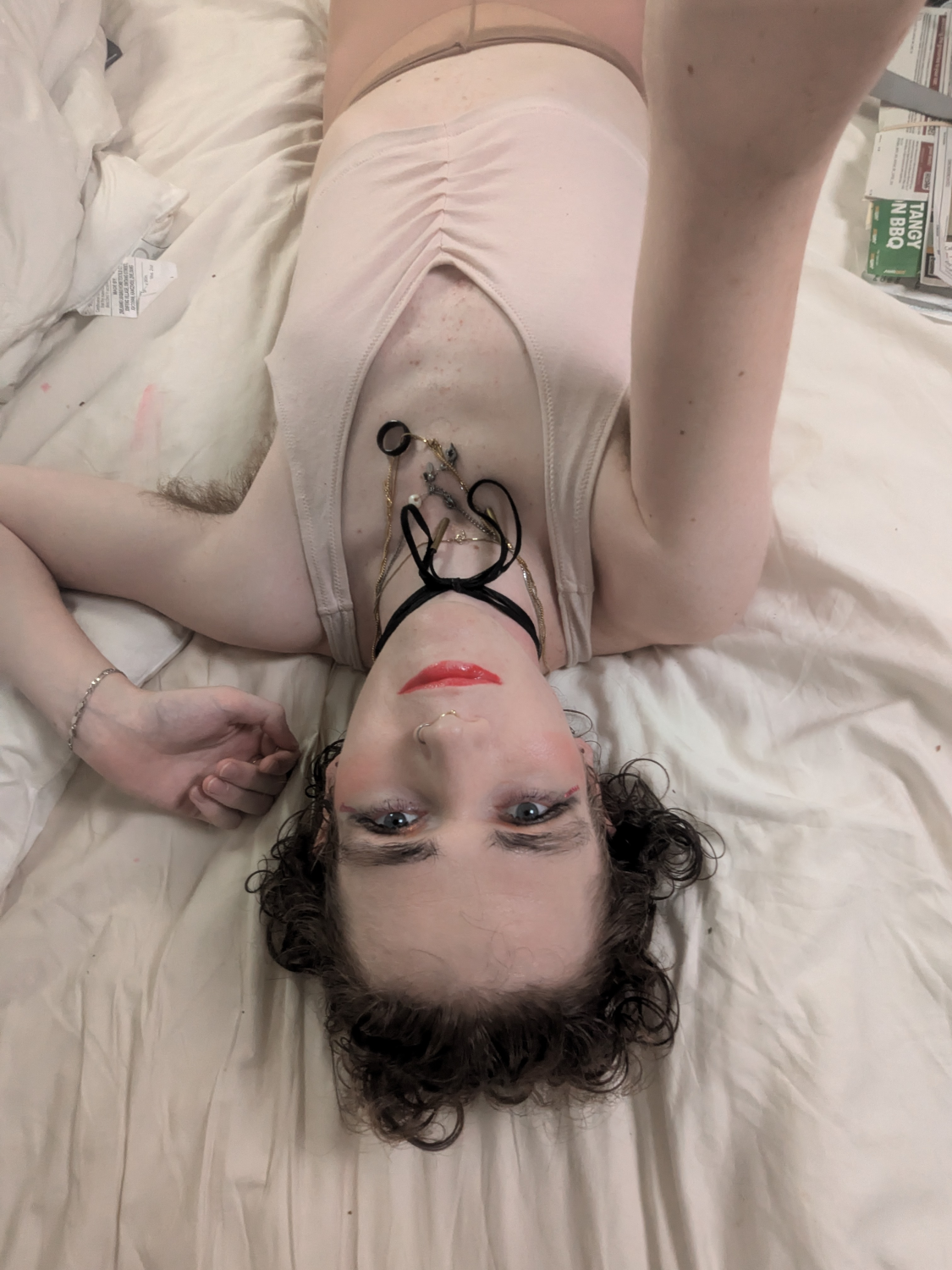 A woman laying on a bed with a tattoo on her face. - by Daisy