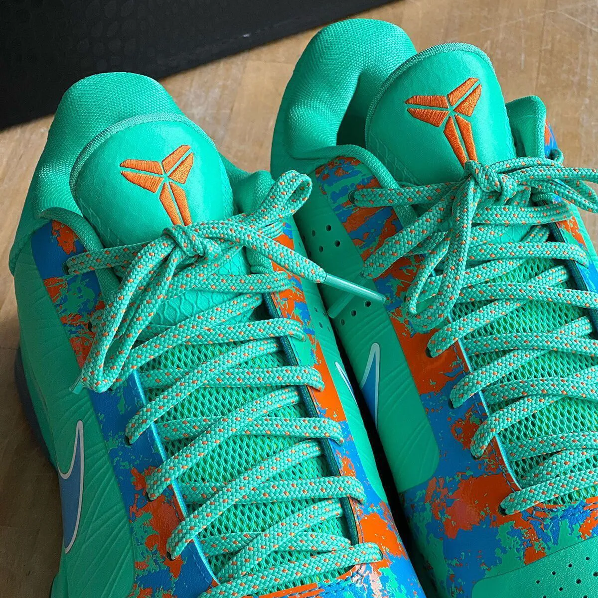 Close-up angle of the Nike Kobe 5 Protro NY vs NY colorway showing orange and blue splatter graphics on the toe box