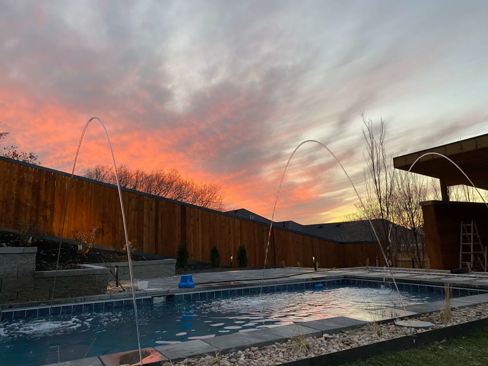 Backyard swimming pool beneath a colorful sunset