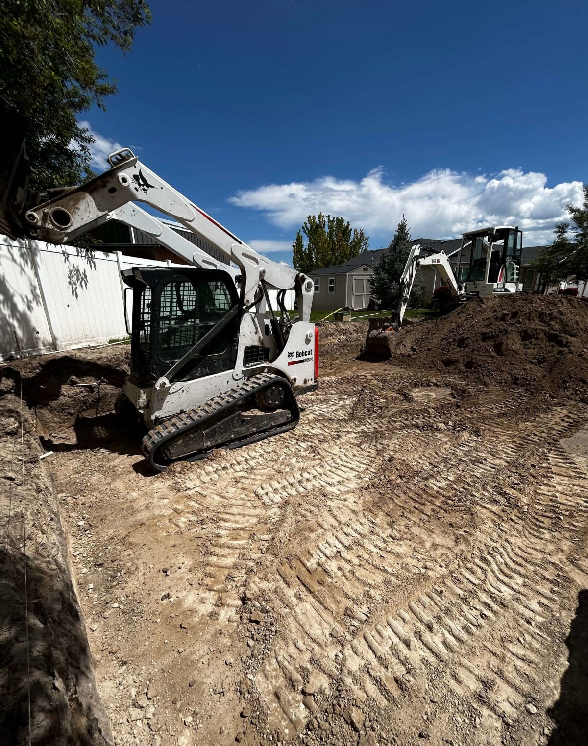 Compact construction equipment grading and excavating a residential yard