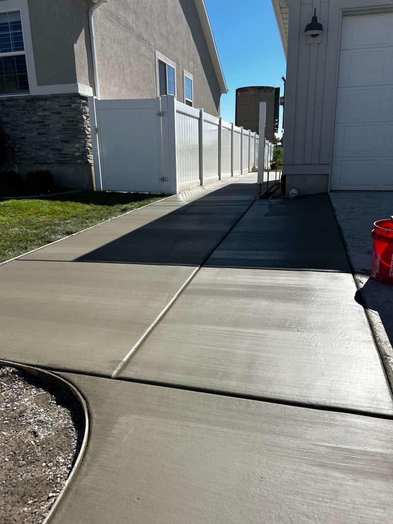 Concrete side driveway and walkway beside white fencing