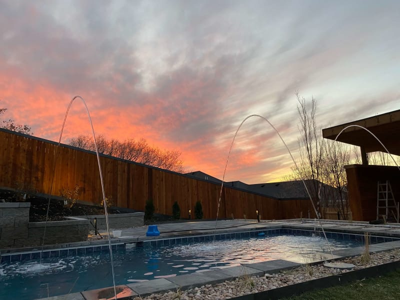 Backyard swimming pool beneath a colorful sunset