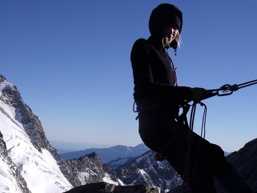 New Zealand Alpine Instruction Courses - Mountaineering & Climbing Instruction Courses - Intensive Mountaineering Skills Course - Learn technical mountaineering skills on an alpine climbing course at Caroline Hut, Aoraki Mount Cook National Park - Silhouette of a female climber abseiling in front of a snow covered mountain, rocky ridge and glacier - Mountaineering Instruction Course, Aoraki Mount Cook National Park 1