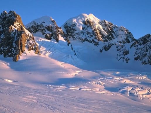 New Zealand Alpine Climbing, Mountaineering Instruction & Guided Ascents - Guided Alpine Ascents in New Zealand - Mount Tasman - Mount Haast, Lendenfeld Peak and Mount Tasman - Majestic snow-capped peaks rise against a brilliant blue sky, with a vast expanse of snow-covered terrain in the foreground. 4
