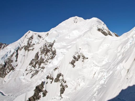 New Zealand Alpine Climbing, Mountaineering Instruction & Guided Ascents - Guided Alpine Ascents in New Zealand - Mount Tasman - Mount Tasman and Lendenfeld Peak - Majestic snow-capped mountain peaks rise against a brilliant blue sky, casting dramatic shadows on the surrounding terrain. 2