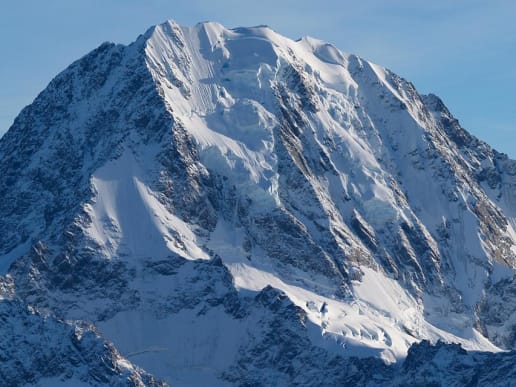 New Zealand Alpine Climbing, Mountaineering Instruction & Guided Ascents - Guided Alpine Ascents in New Zealand - Guided Ascents - Malte Brun - New Zealand guided ascents - A majestic, snow-capped mountain peak rises against a clear blue sky, its rugged, jagged edges and steep slopes covered in a pristine layer of snow. 1