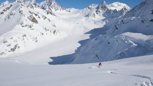New Zealand Mountain Adventures | Guided winter experiences in the Southern Alps - Backcountry skier skiing down fresh powder snow above the Murchison Glacier, Aoraki Mount Cook National Park 1