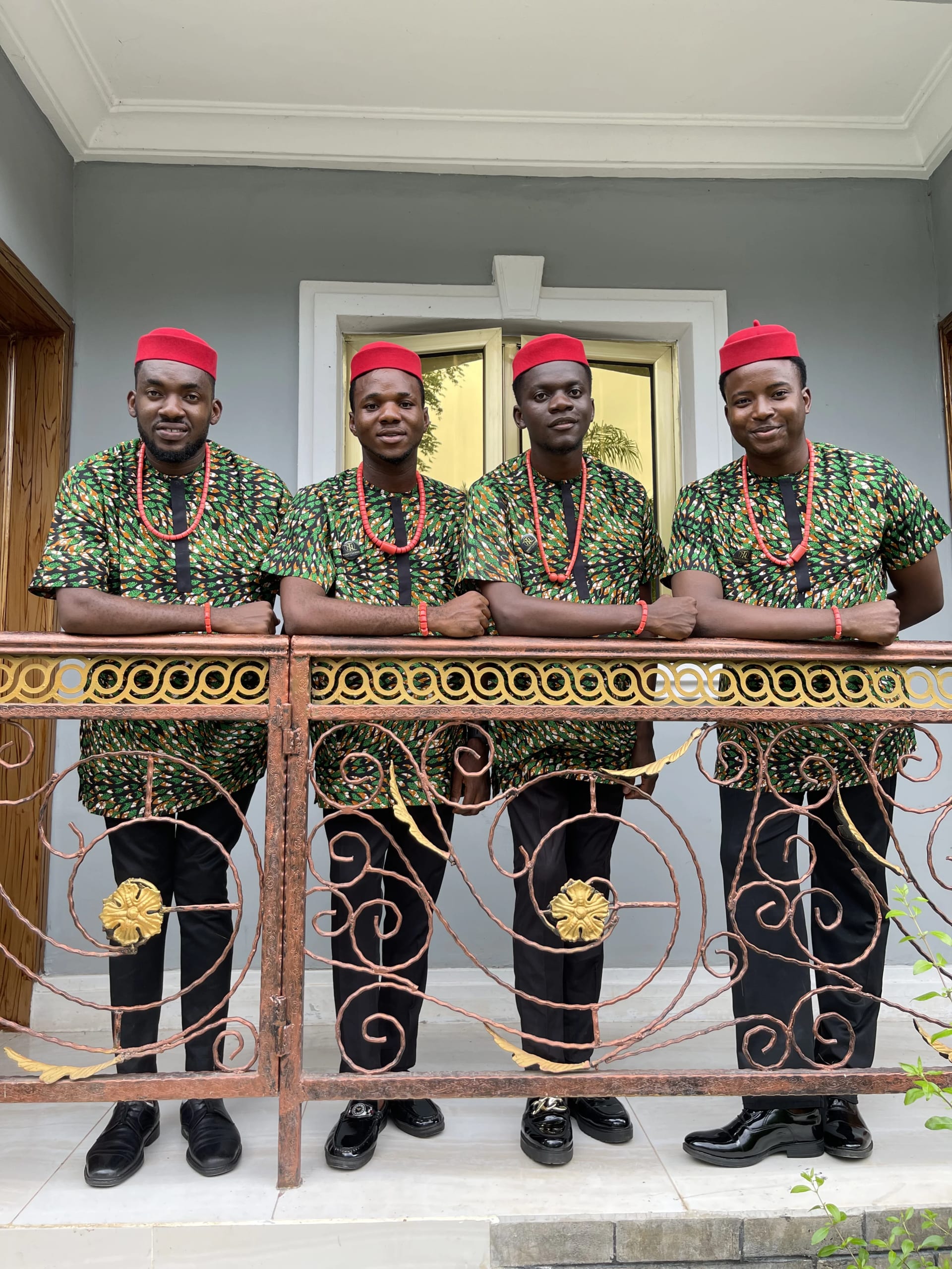 Male ushers in green Ankara and red caps