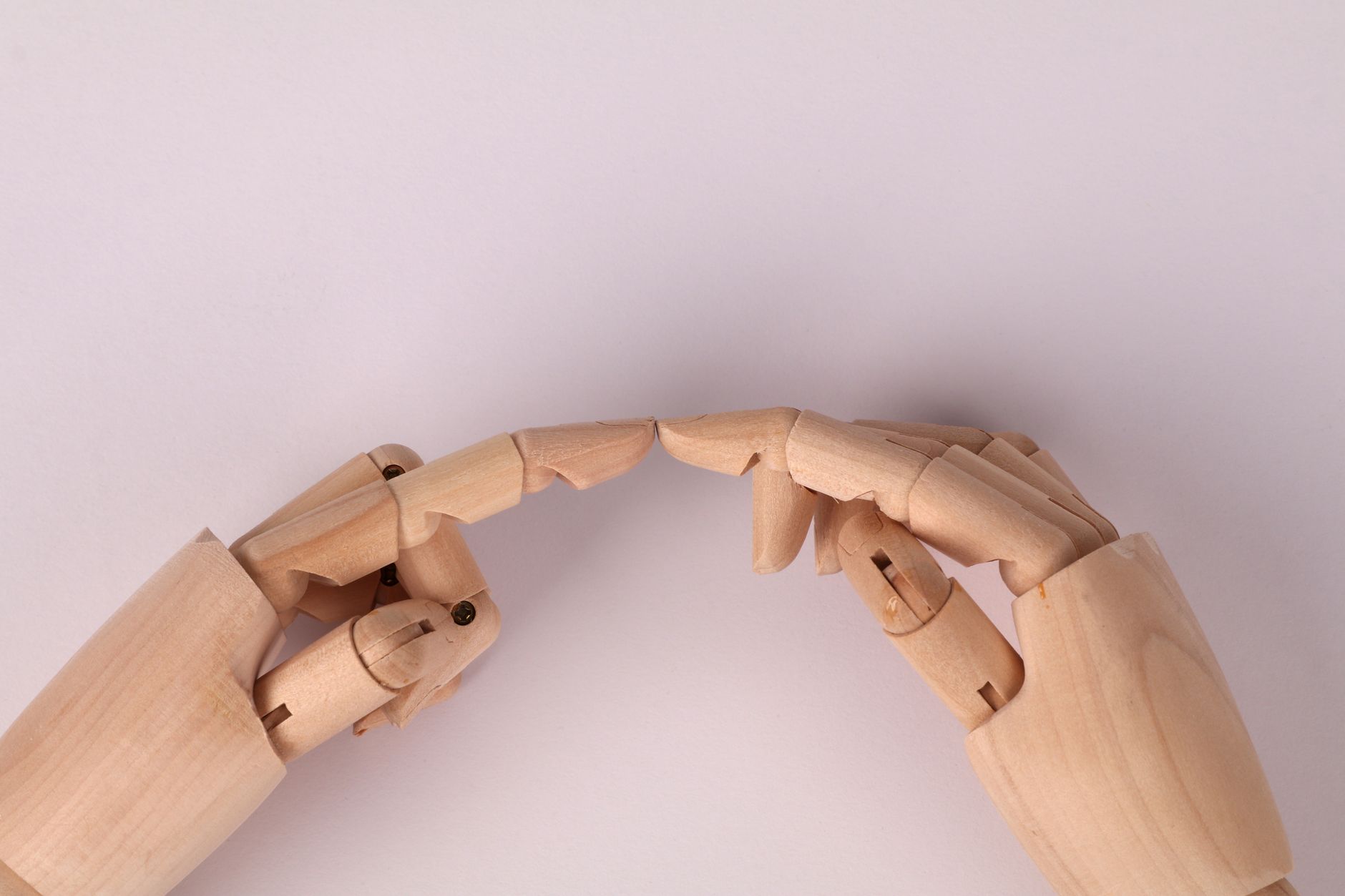 Close-up of wooden mannequin hands almost touching, capturing a concept of connection.