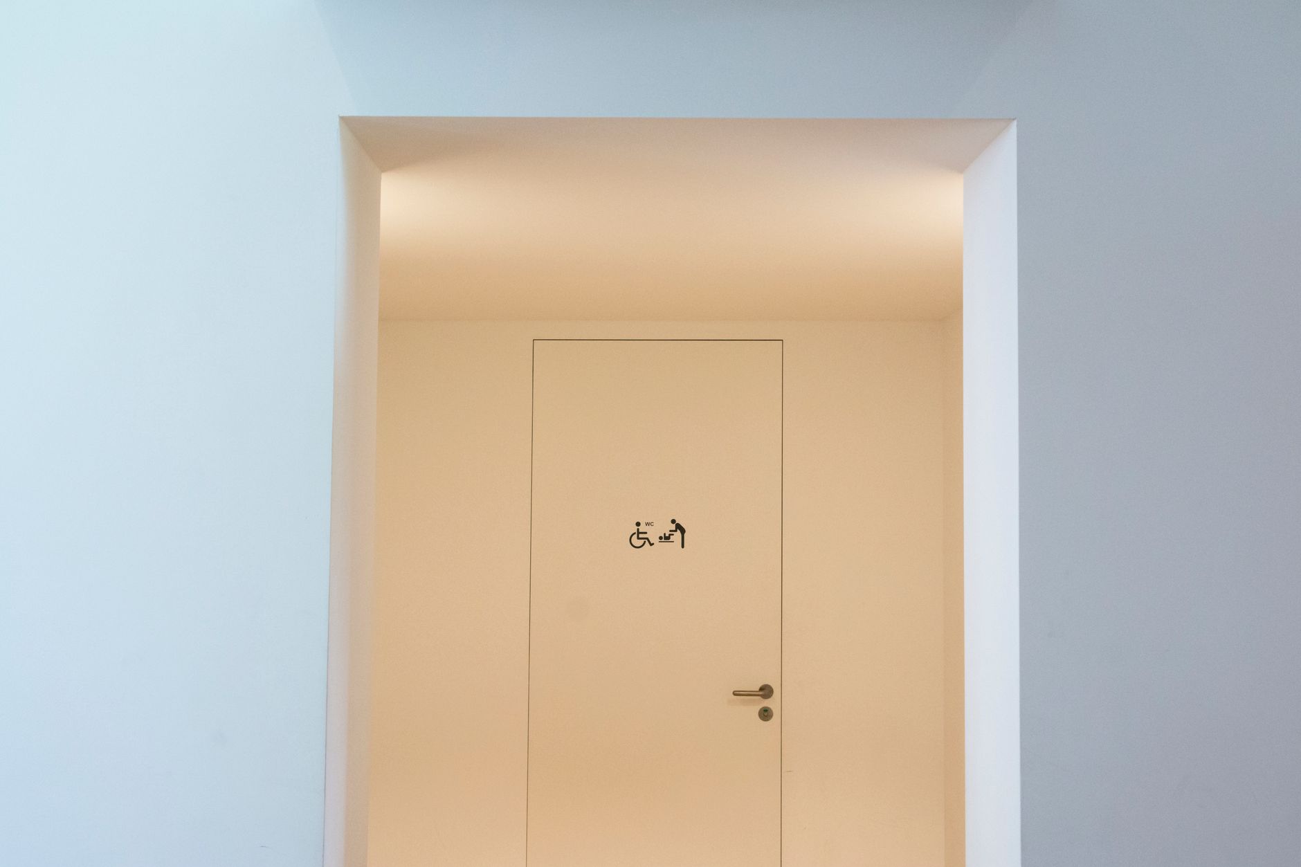 A clean and minimalist indoor space featuring an accessible restroom sign on a closed door.