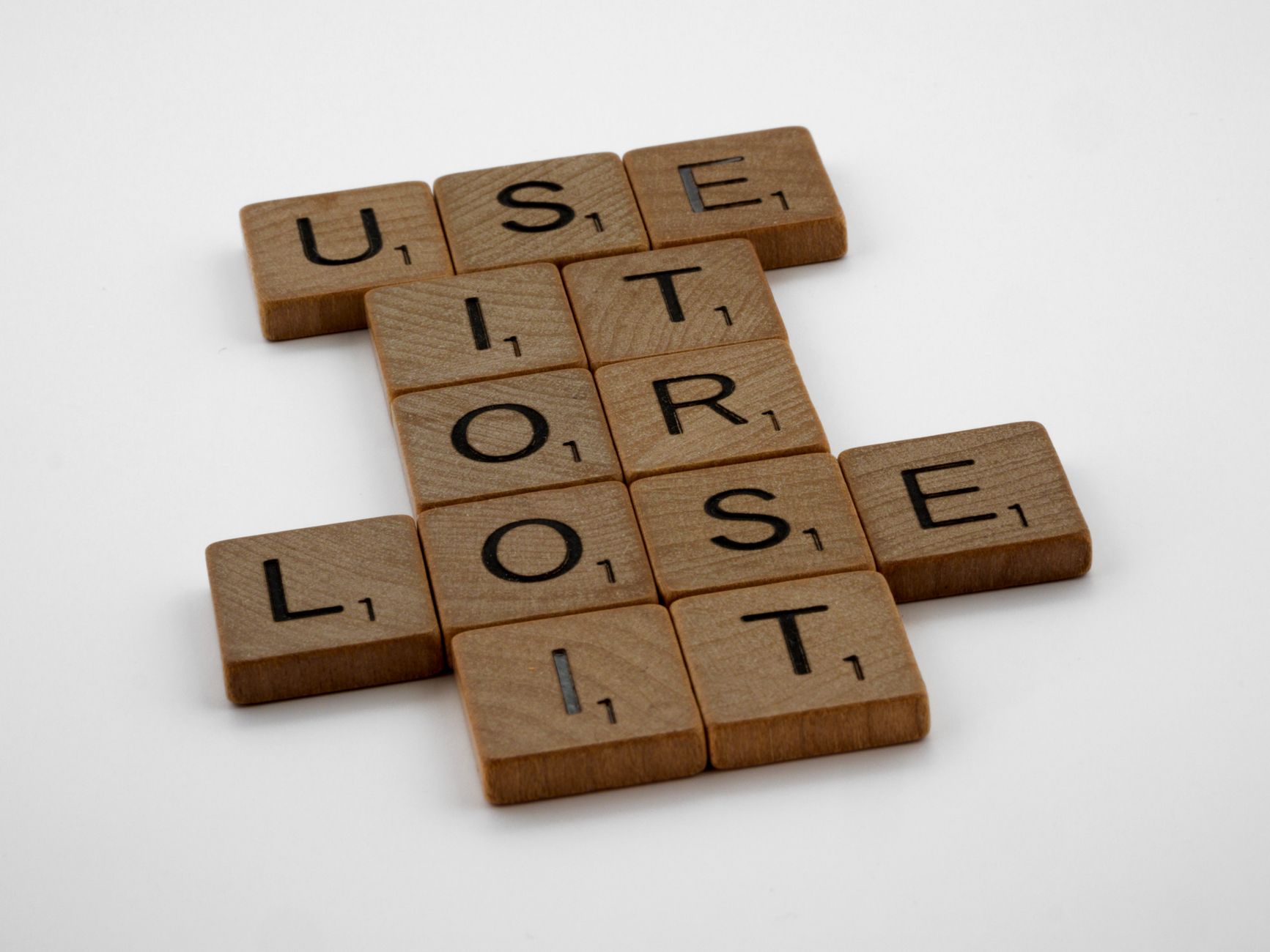 Arrangement of scrabble tiles spelling 'use it or lose it', encouraging motivation and creativity.