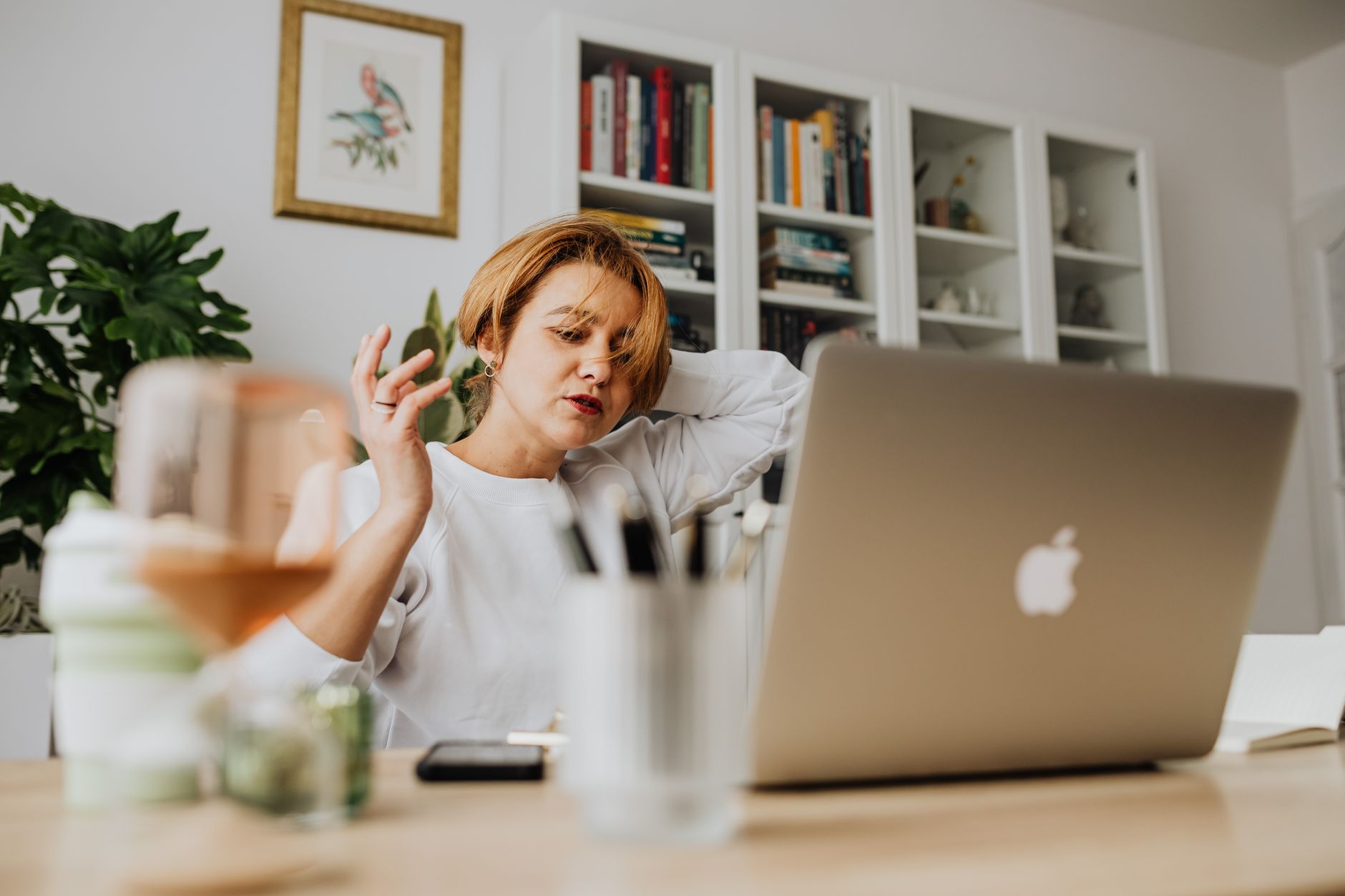 A woman feeling stressed while working from home with a laptop in a modern living room.