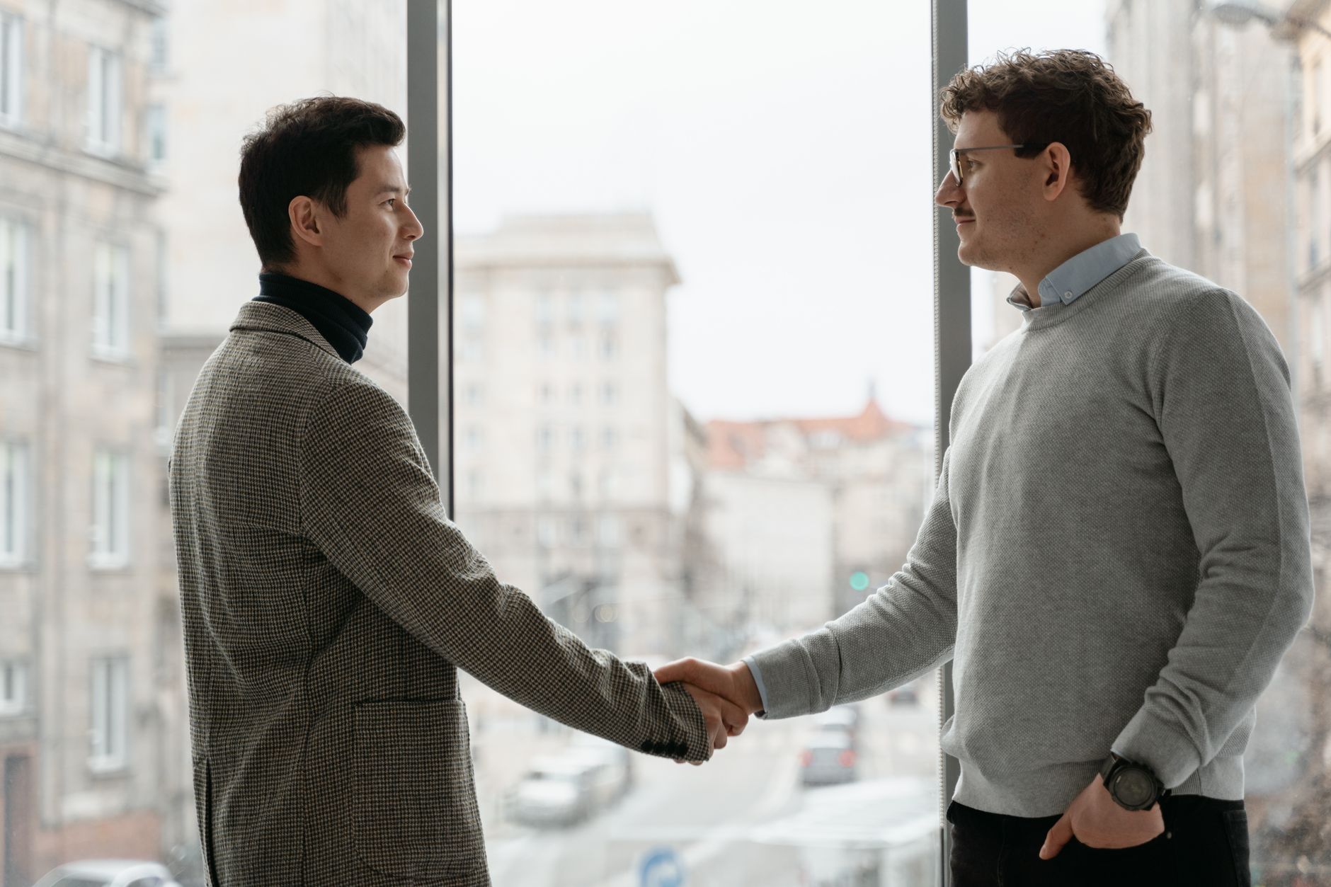 Two businessmen shaking hands in a modern office, symbolizing a successful partnership.