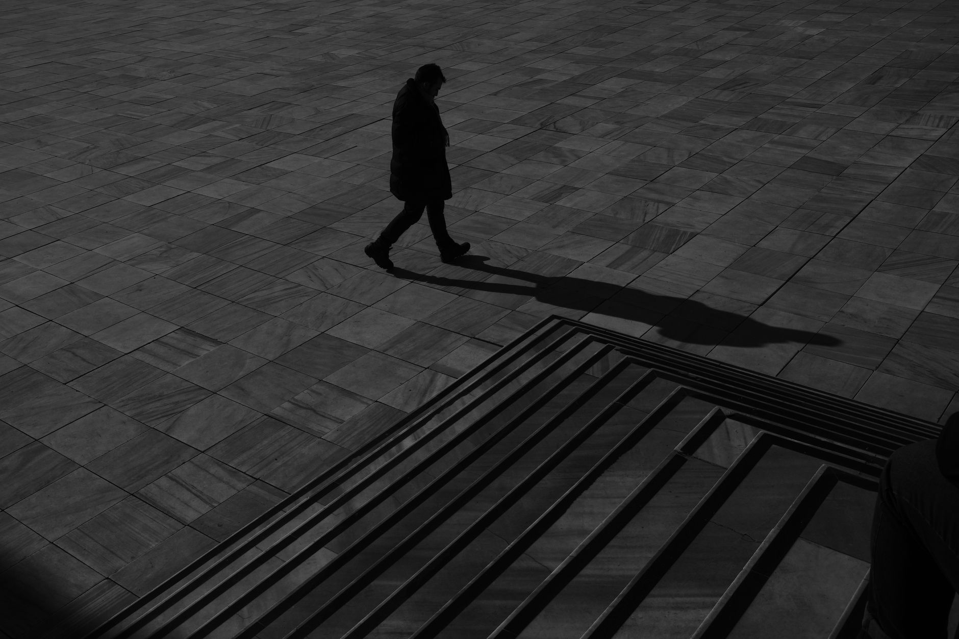 A lone silhouette walks near a staircase in Ankara, Türkiye, casting a dramatic shadow.