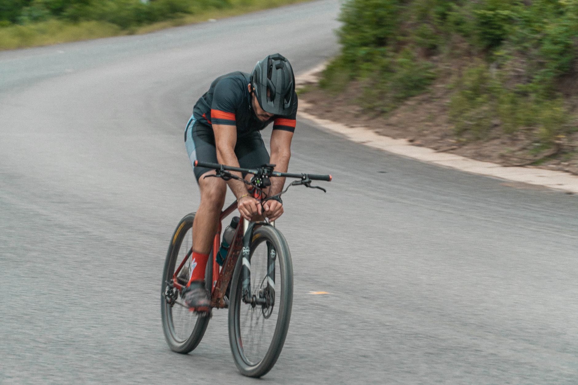 Cyclist racing on a mountain bike on a winding road during the day.