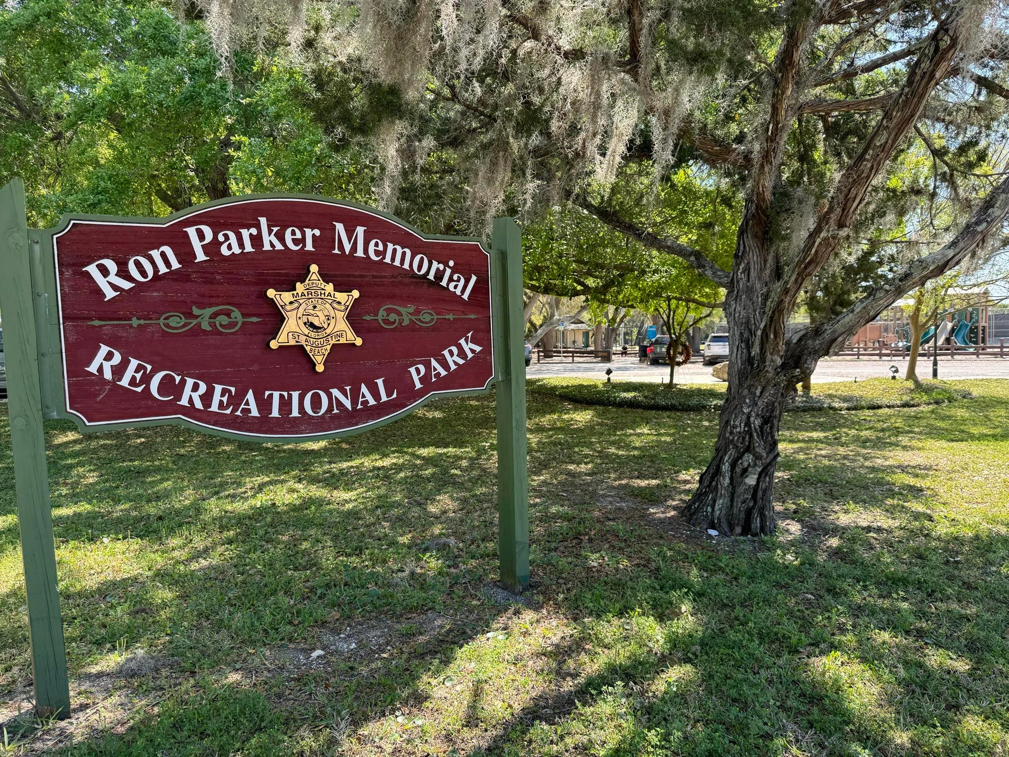 Ron Parker Park sign with playground equipment behind it