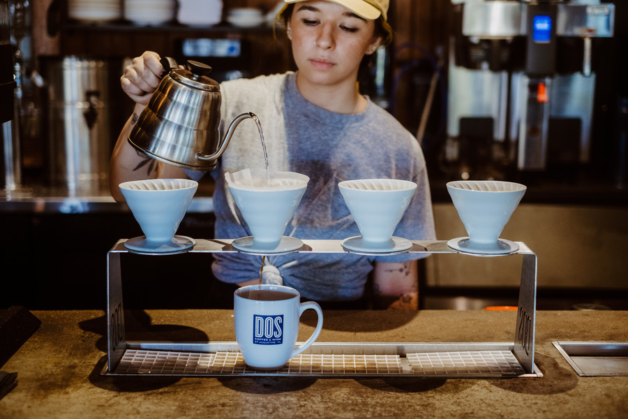 A barista pours coffee at DOS Coffee & Wine