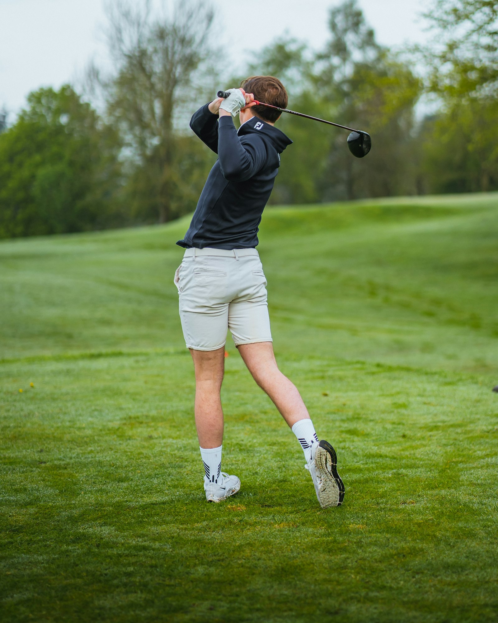 A golfer shapes a shot across the practice fairway.