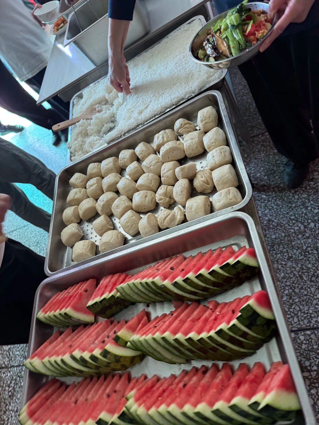 Students lining up for a simple cafeteria lunch with steamed buns, rice, vegetables, and watermelon at a Tai Chi school in Chenjiagou.