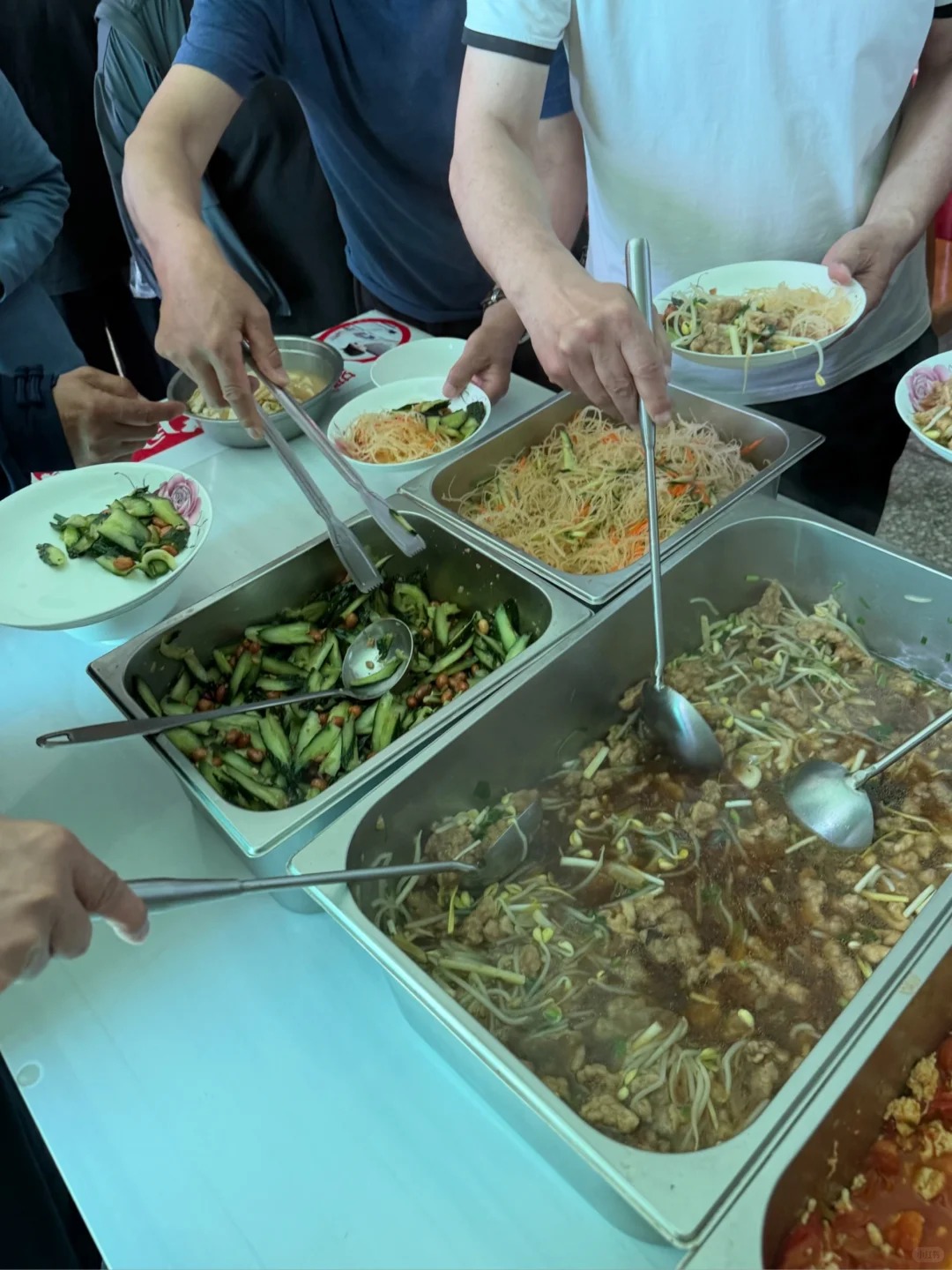 Students serving themselves noodles, cucumber salad, and hot dishes during lunch at a Tai Chi training school in Chenjiagou.