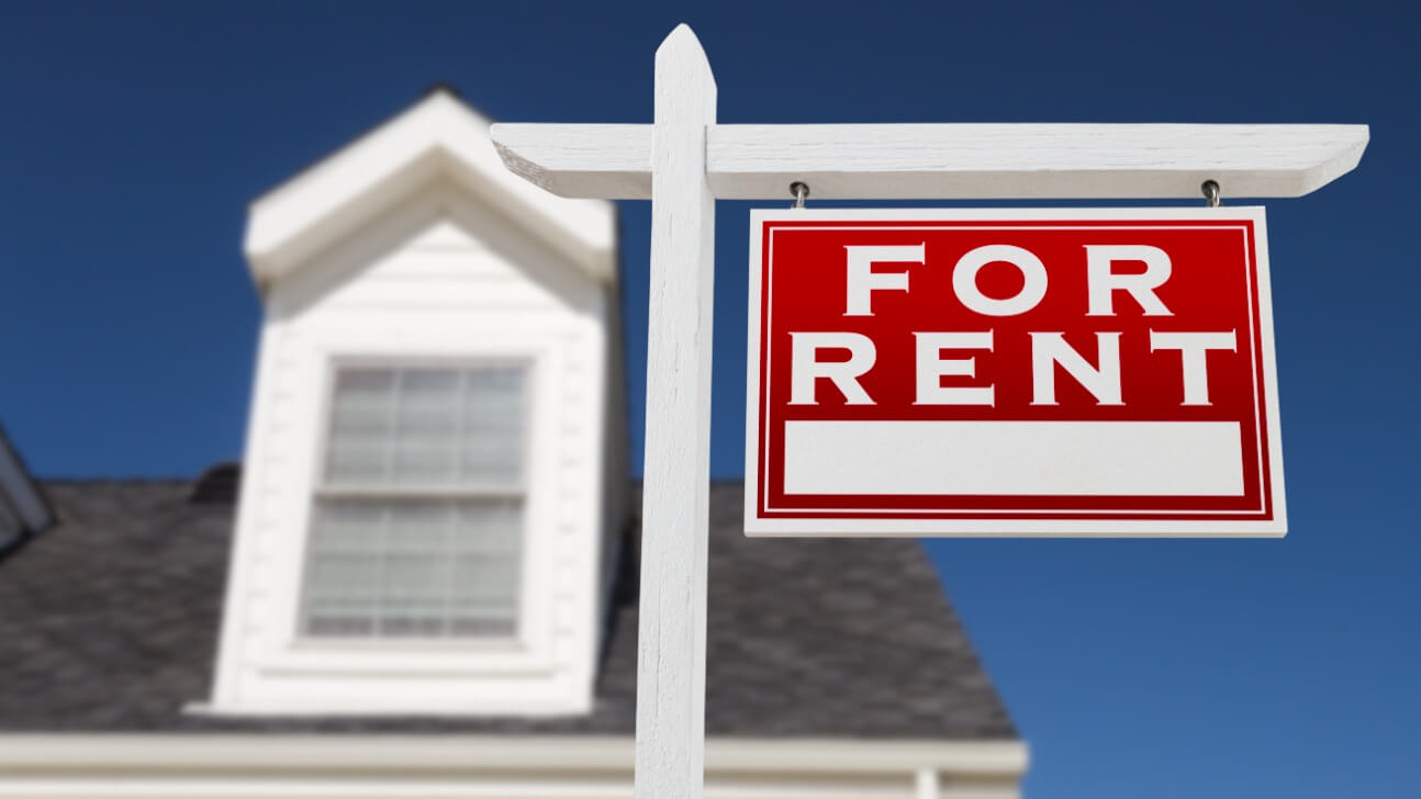 right facing for rent real estate sign in front of house and