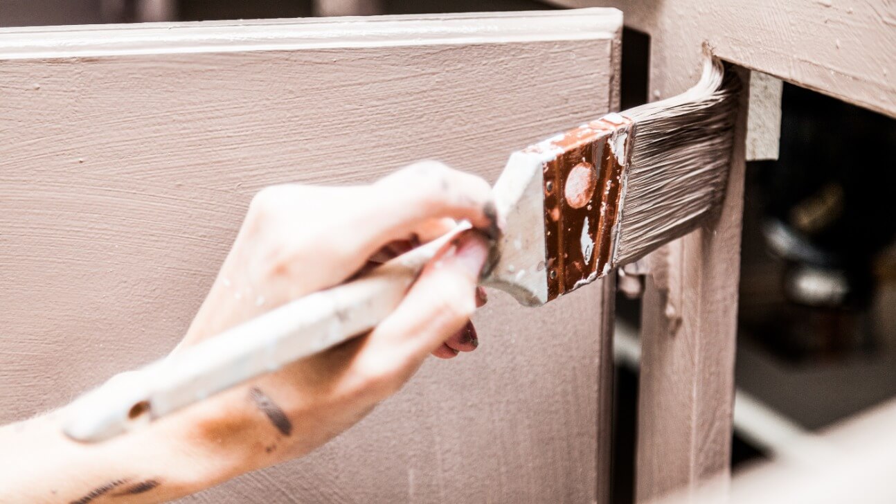 closeup of person painting kitchen cabinets