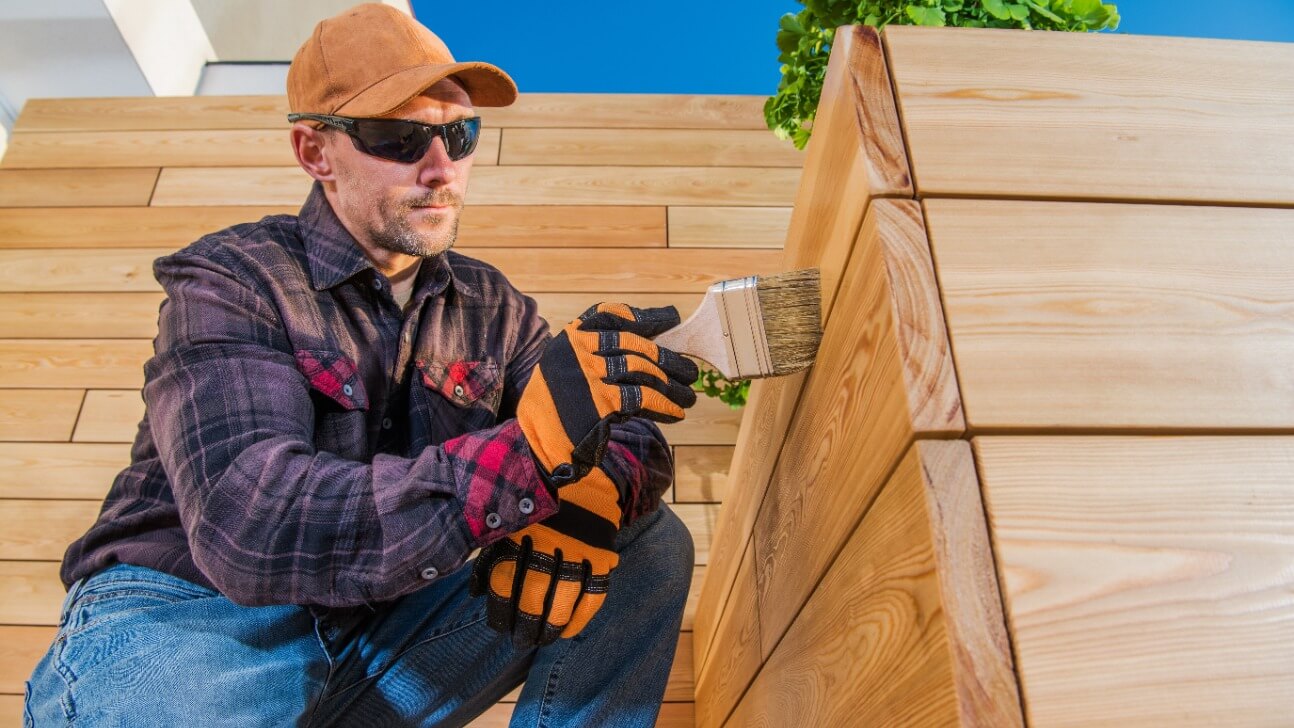 painter oiling wooden planks with brush