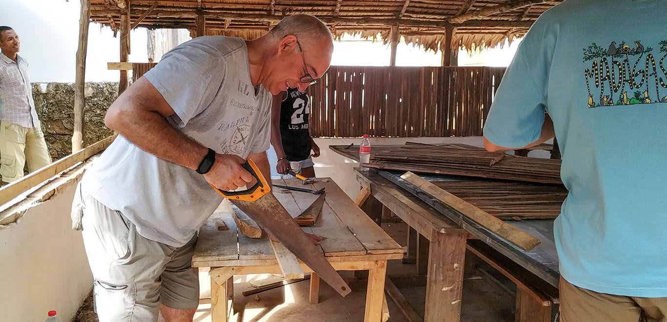 Volunteer cutting wood with a saw 