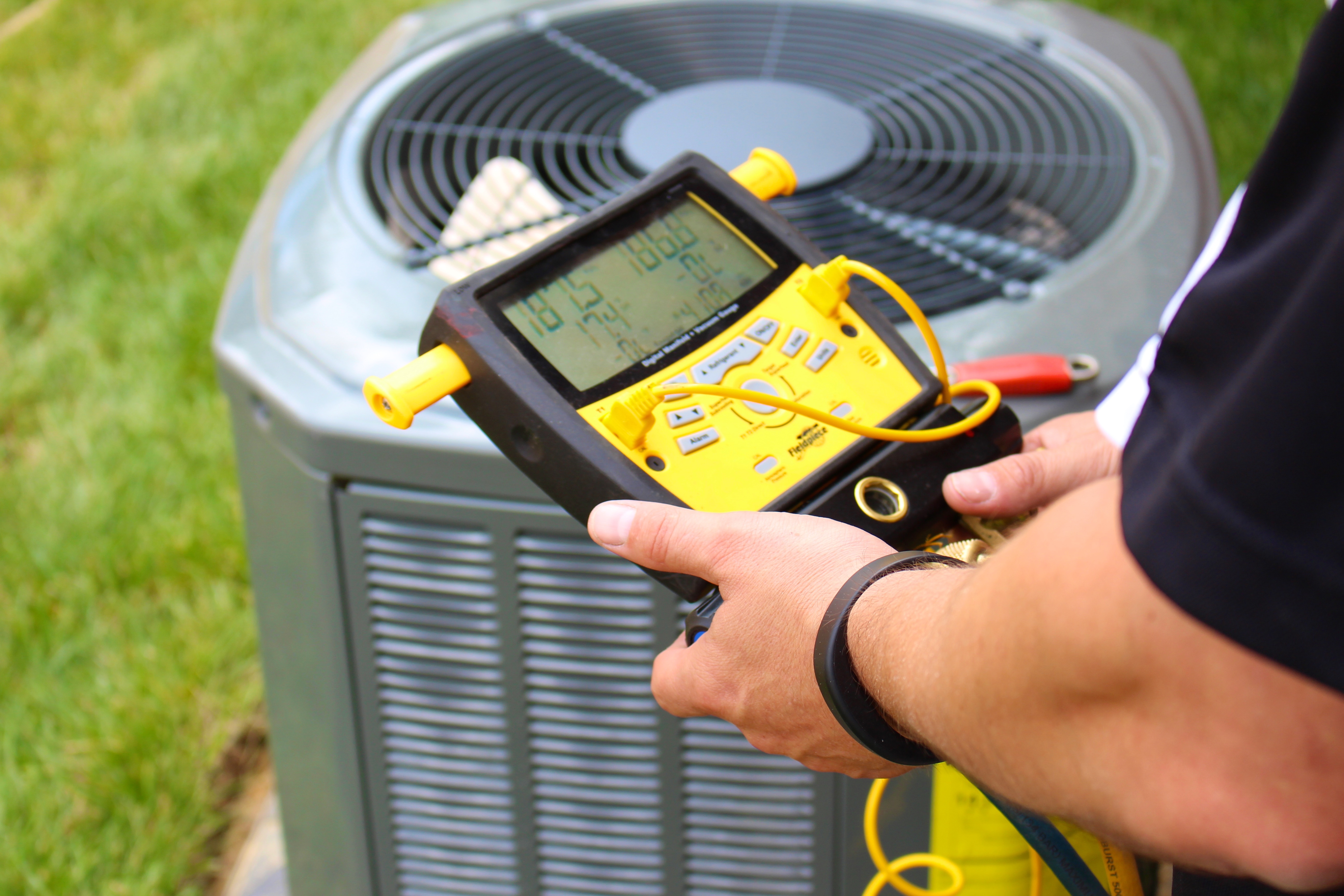 New AC condenser being placed outside a home, with technician and equipment