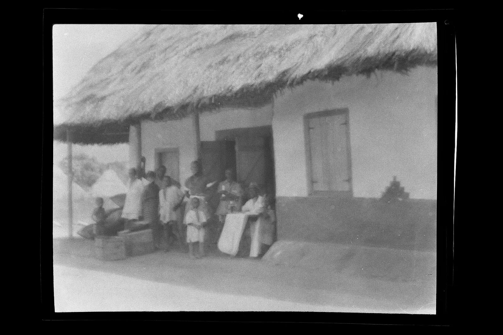 Group assembled by doorway to house, looking at camera