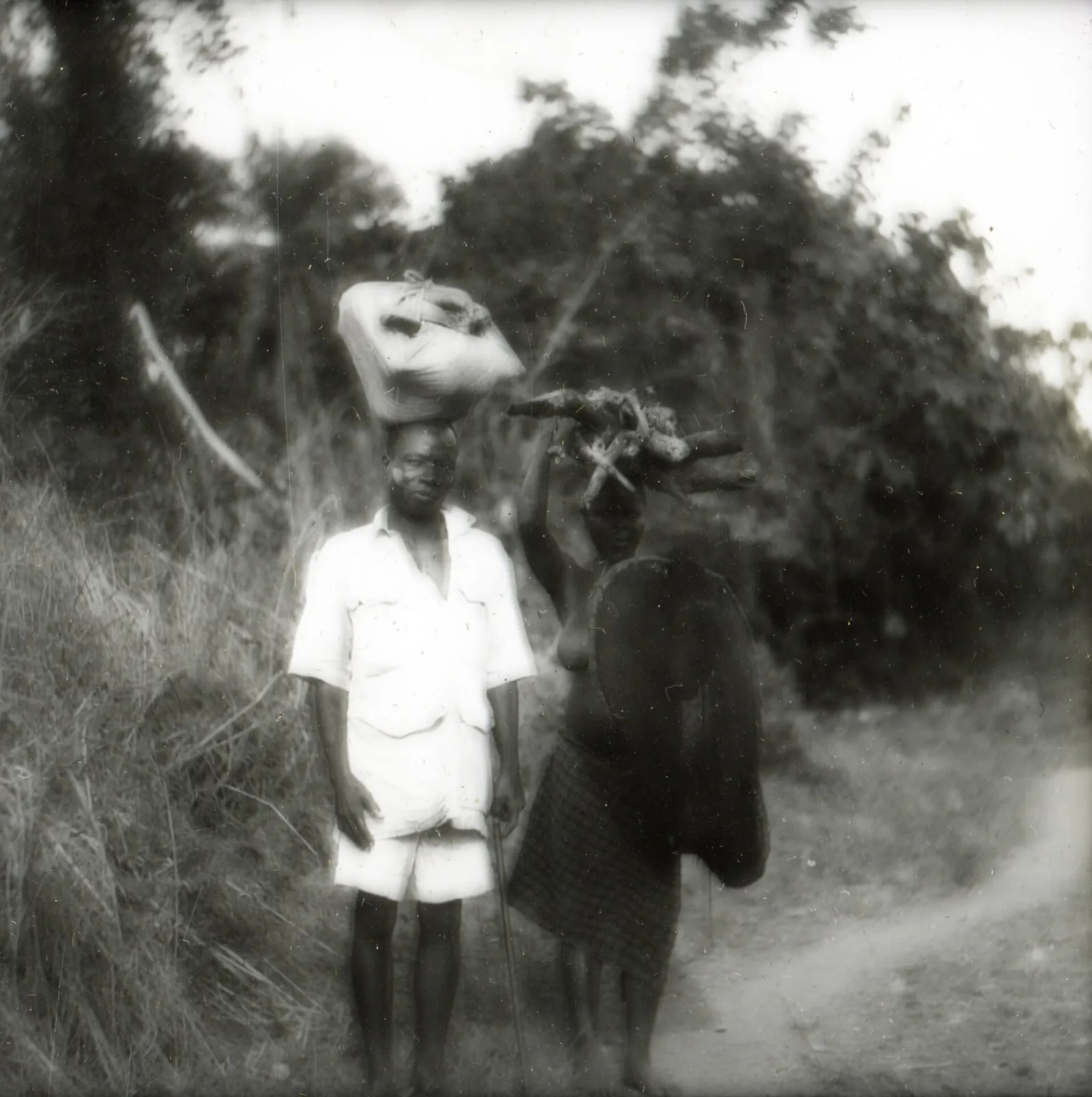 Two people carrying loads on their heads, Panguma