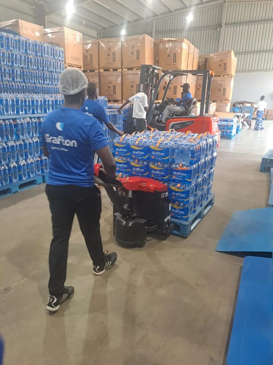 Employees stacking crates of water at the Grafton Spring water factory
