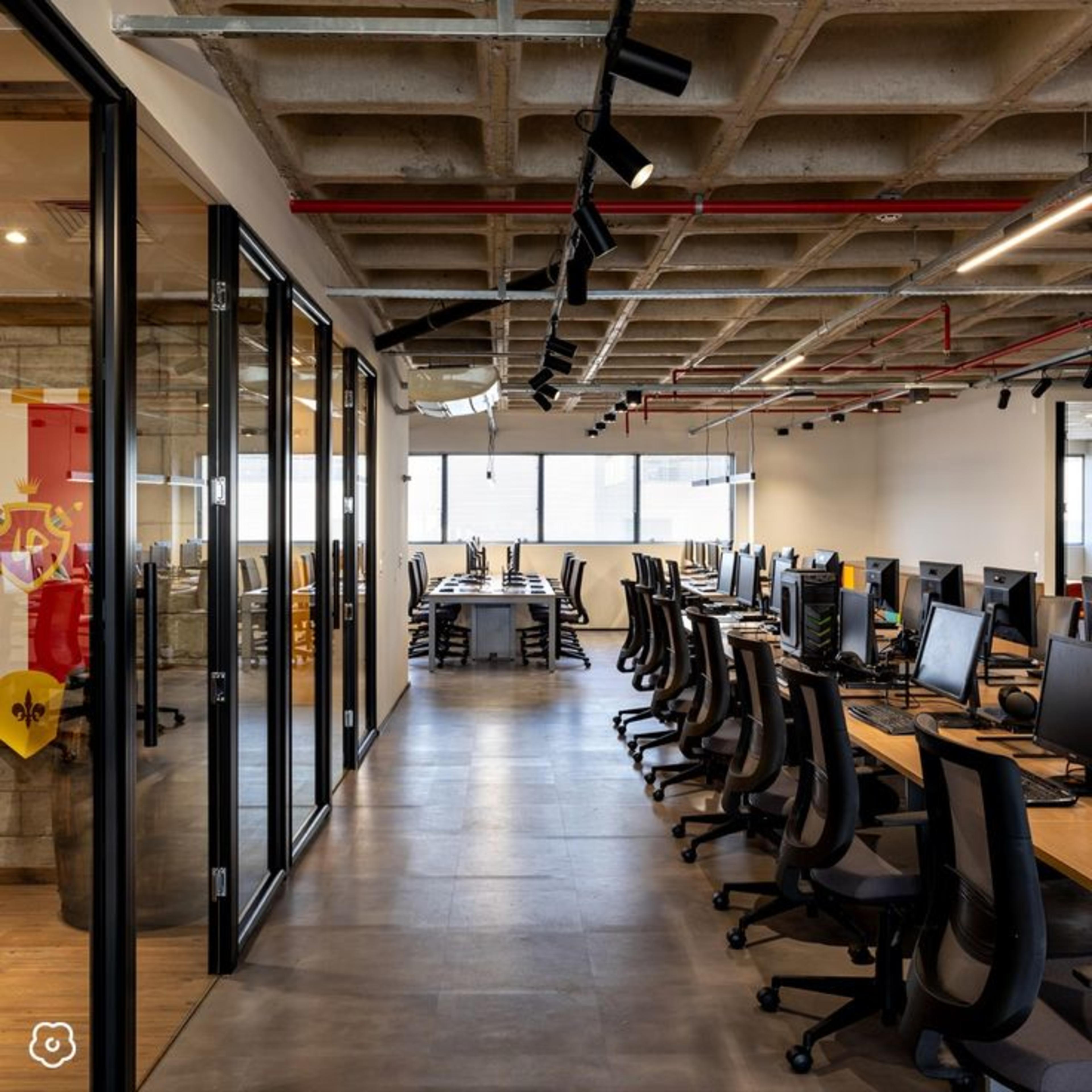Virtual office in HSR Layout featuring a spacious setup with wooden desks chairs and glass wall interiors