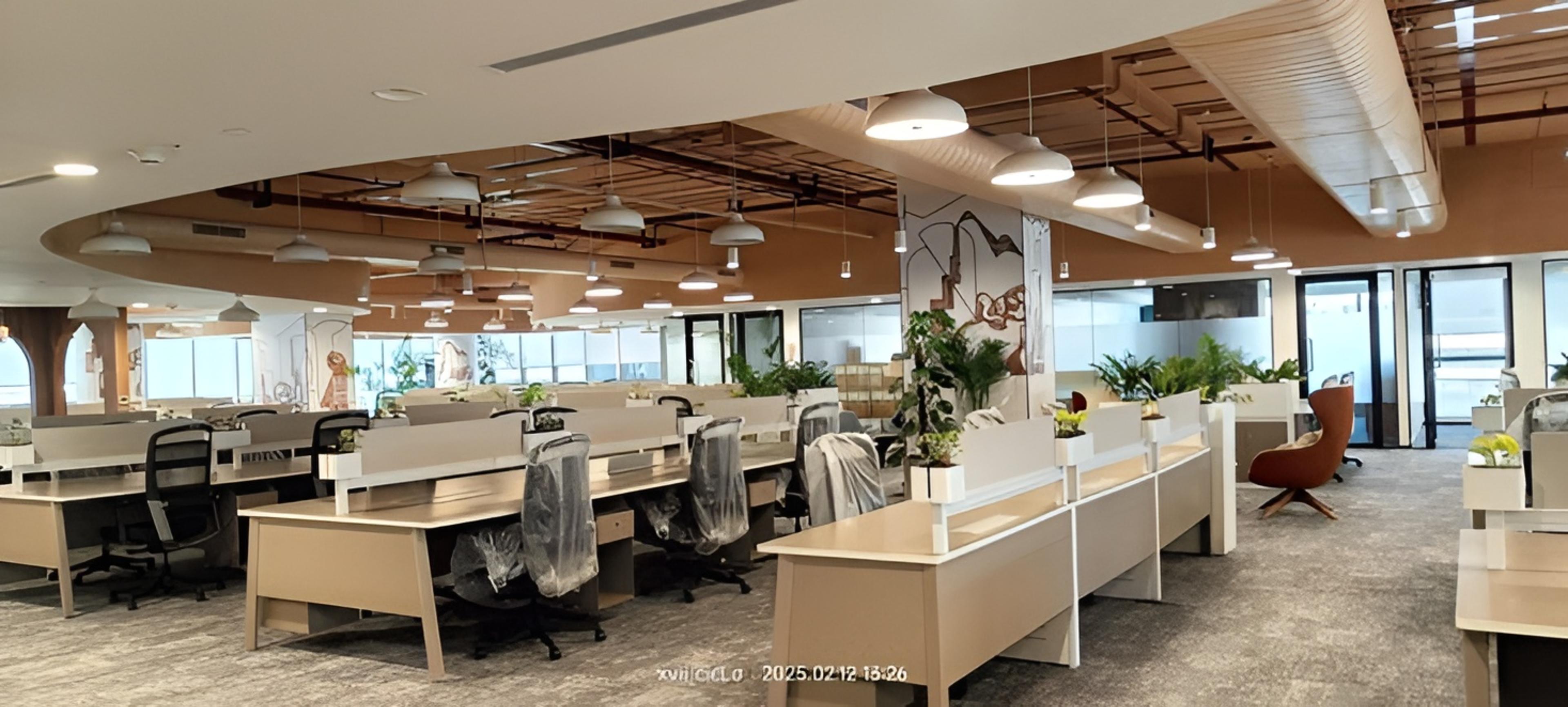 Coworking Day Pass in HSR Layout featuring ash chairs light brown desks green plants and a brown ceiling with ambient lighting