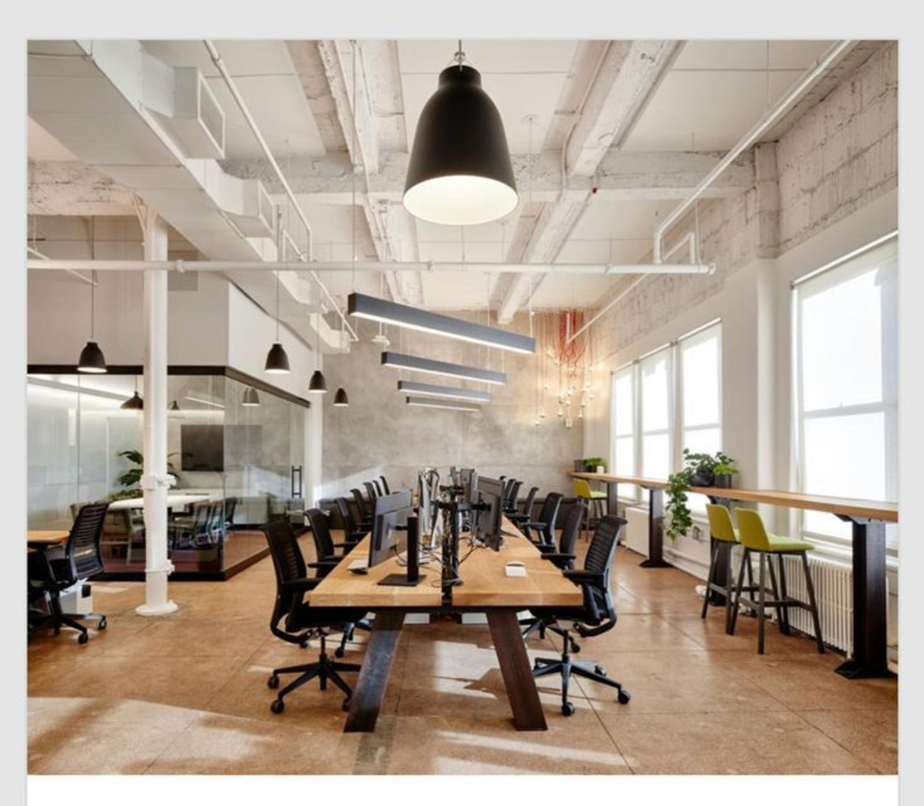 Private cabin coworking space featuring white interiors, wooden desks and black chairs in a modern office space