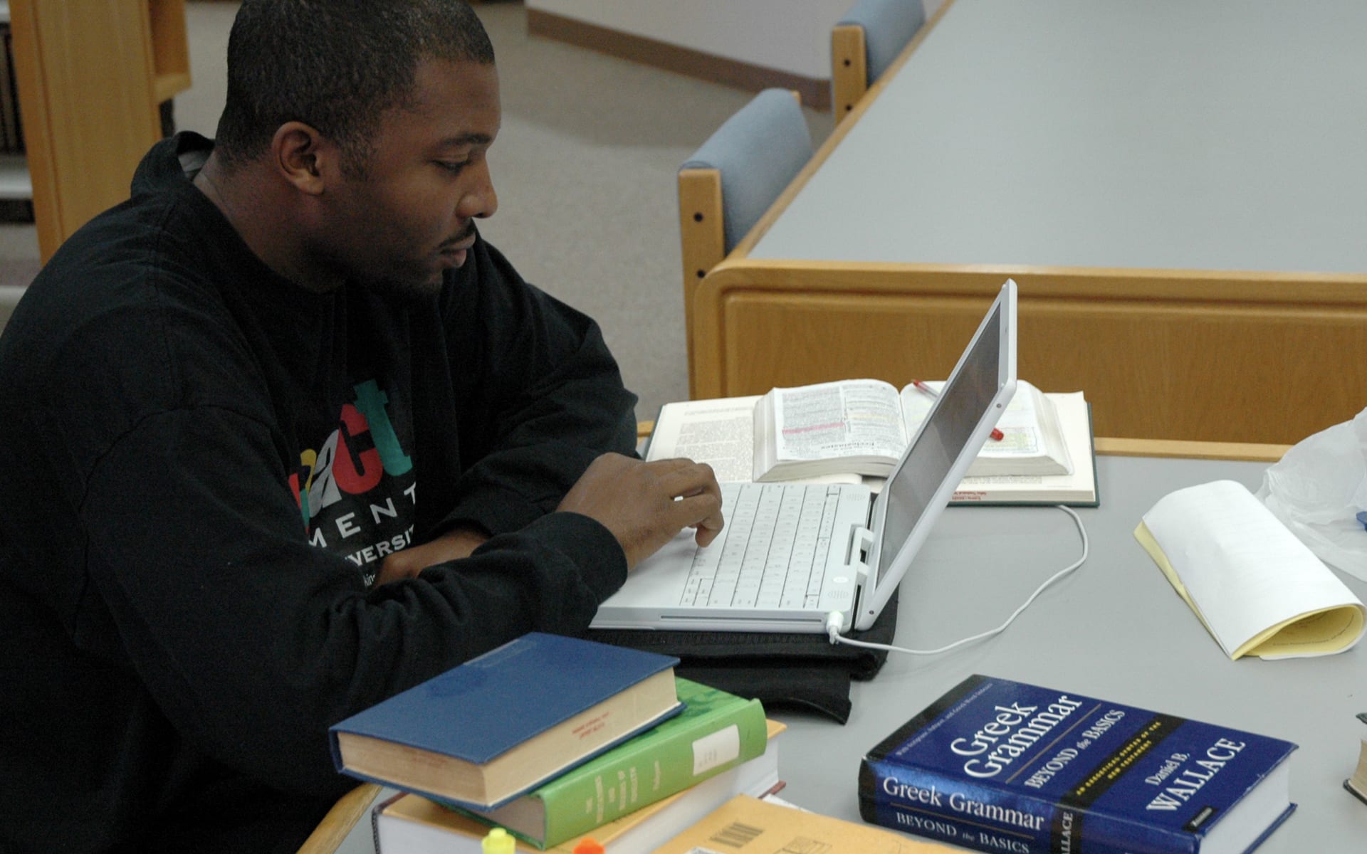 man studying at a table in the library with his laptop