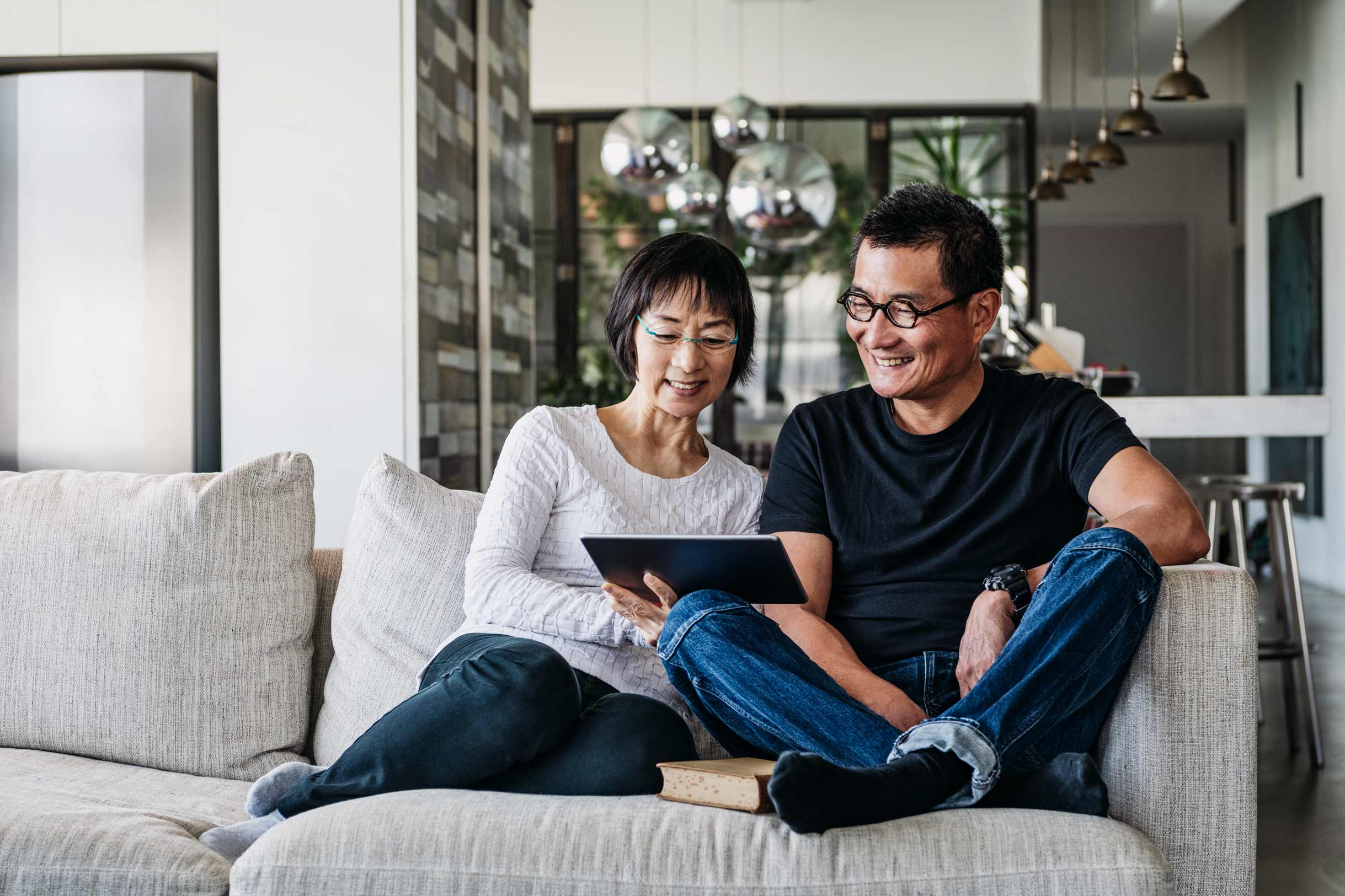 Chinese couple sitting on a couch reading a book
