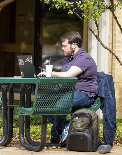 man sitting on a bench in front of Walvoord Hall
