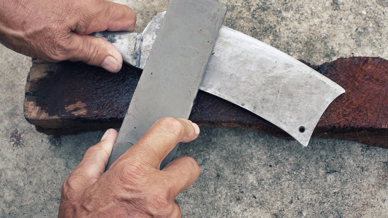 two hands sharpening an ax